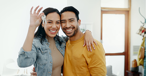 Happy couple holding house keys after property purchase with Eagle Peak Conveyancing support.